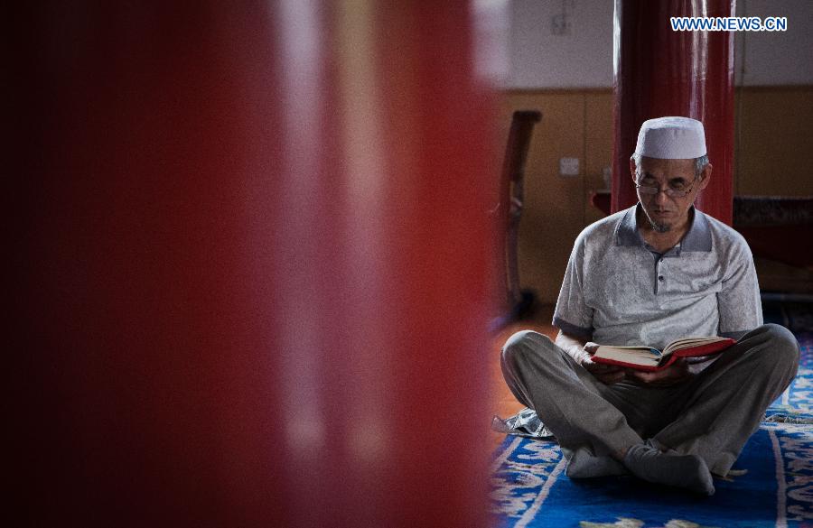A Muslim reads scriptures at the Qingzhenzhongsi Mosque in Yinchuan, capital of Ningxia Hui Autonomous Region, July 3, 2014. Built in 1931, the mosque was located in downtown Yinchuan and known for its ancient-style architectures. [Photo/Xinhua]