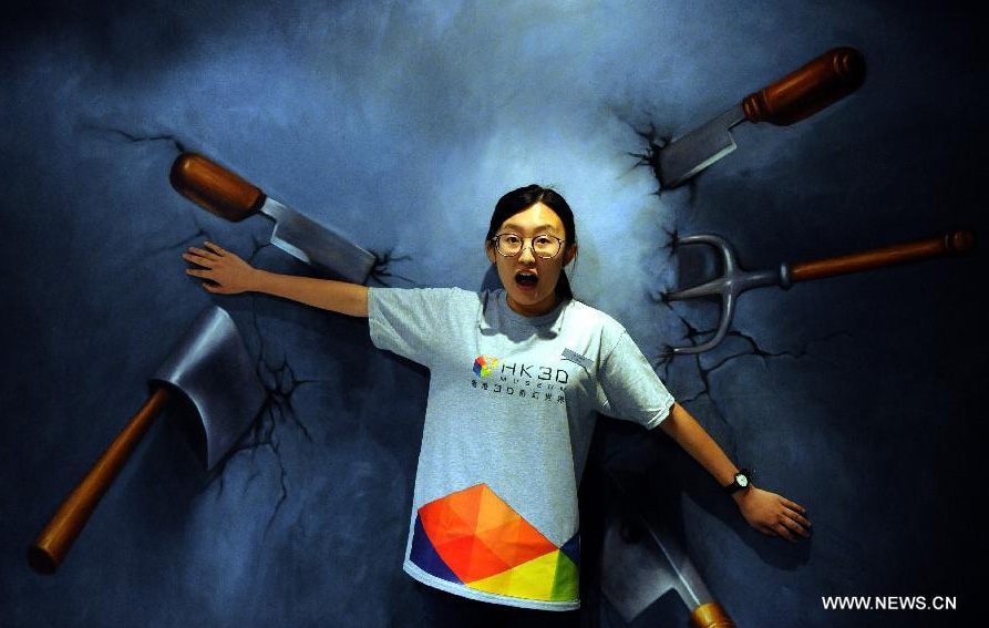 A visitor poses for a photo in front of a 3D image at the HK 3D Museum in Hong Kong, south China, June 26, 2014. The 3D art museum, the first of this kind in Hong Kong, was unveiled here on Thursday. [Photo/Xinhua]