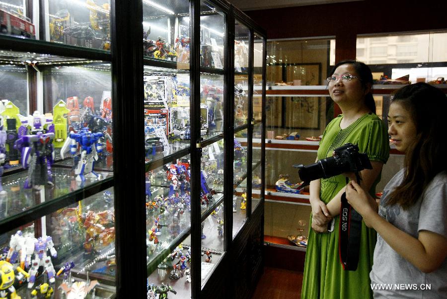 Visitors look at Transformer toys displayed at an old toy exhibition in east China's Shanghai, July 2, 2014. The toys presented on the exhibition, from the collections of 18 collectors, remind visitors born in the 1970s and the 1980s of their childhood. [Photo/Xinhua]